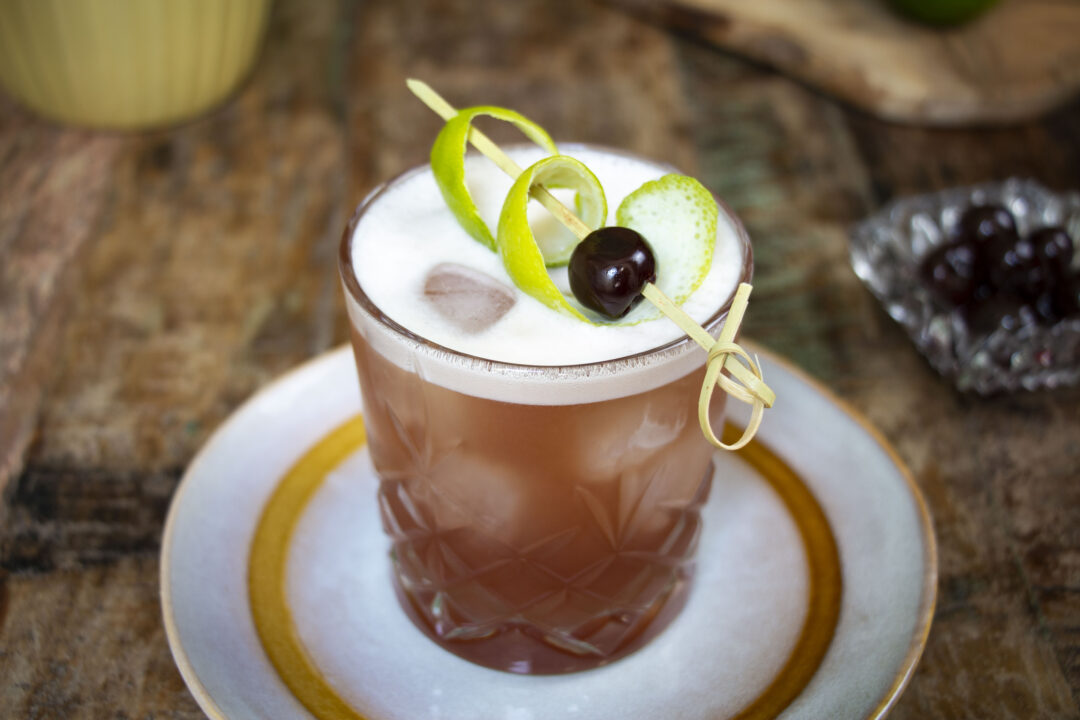 Norma Jennings cocktail, close up, from top with amarena cherry and lime peel garnish