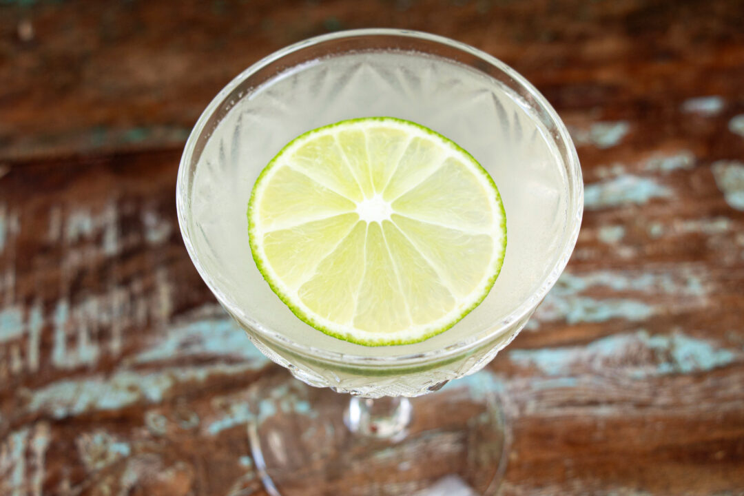 An overhead shot of a gimlet cocktail with a lime slice garnish